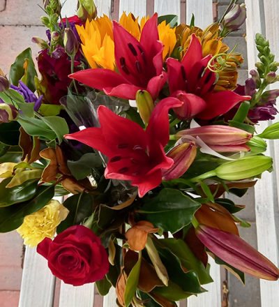 Hot Summer - A vibrant container arrangement, created using the fresh blooms of the day in a mix of orange, purple, red and green with complementary foliage.